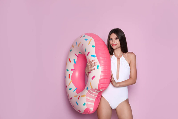 Sexy young woman in bikini with inflatable ring on color background - Foto, Imagem