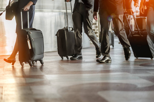 Close up of businessman team carrying suitcase while walking through a passenger boarding bridge.people and traveling luggage walking in airport terminal building - Φωτογραφία, εικόνα
