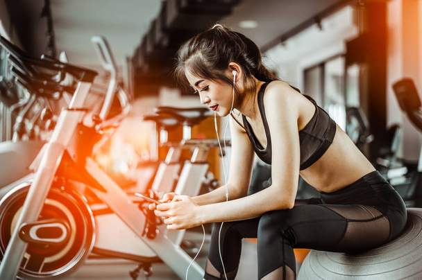 Portrait of Fitness woman  in gym listening to music.exercising concept.fitness and healthy lifestyle  - Фото, изображение
