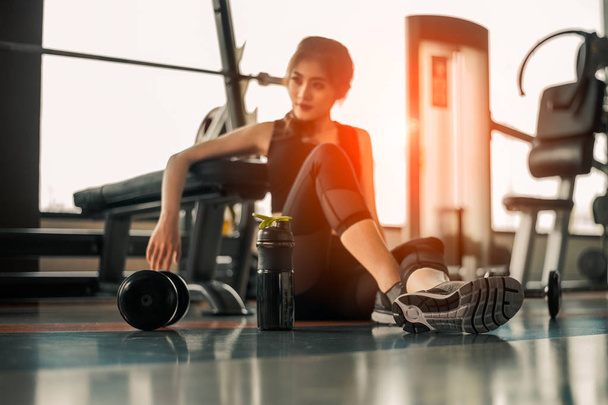 Relaxing after training.beautiful young woman looking away while sitting  at gym.young female at gym taking a break from workout. - 写真・画像