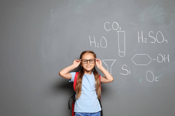 Little school child with backpack and chemical formulas on grey background - Foto, Imagen