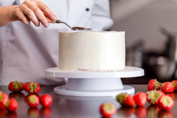 Pastry chef, makes a wedding cake with his own hands and decorates him with berries and flowers. Background image. Copy space. Selective focus. - Foto, immagini