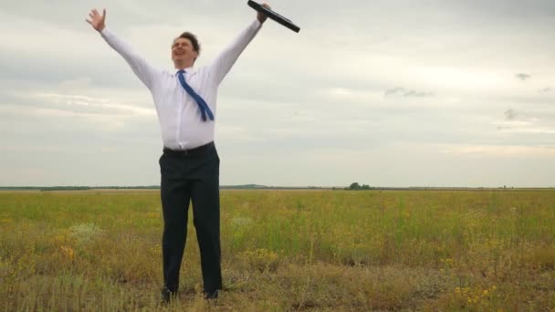Empresario en camisa blanca y corbata con maletín en mano bailando torbellino en vuelo sobre fondo de nubes oscuras y sonriente
 - Metraje, vídeo