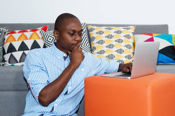 Thinking african american man with laptop at home - Фото, зображення