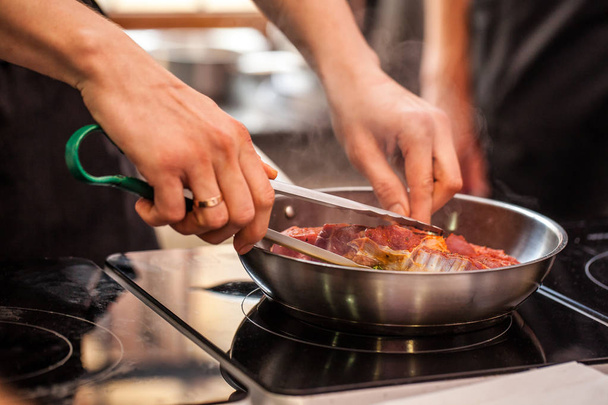 Concept of the correct cooking of meat. The chef prepares, fries a steak of mutton, pork or veal in a frying pan on an induction cooker, with the addition of spices, marinade and wine. Selective focus - Foto, Bild