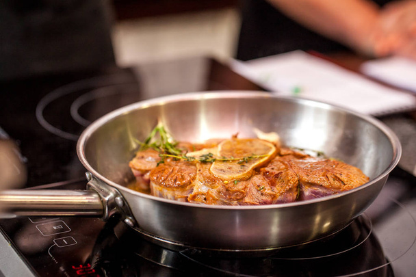 Concept of the correct cooking of meat. The chef prepares, fries a steak of mutton, pork or veal in a frying pan on an induction cooker, with the addition of spices, marinade and wine. Selective focus - Photo, image