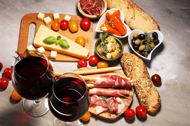 Italienische Antipasti Wein Snacks Set. Käsesorte, mediterrane Oliven, Crudo, Parmaschinken, Salami und Wein in Gläsern über steinernem Grunge-Hintergrund - Foto, Bild