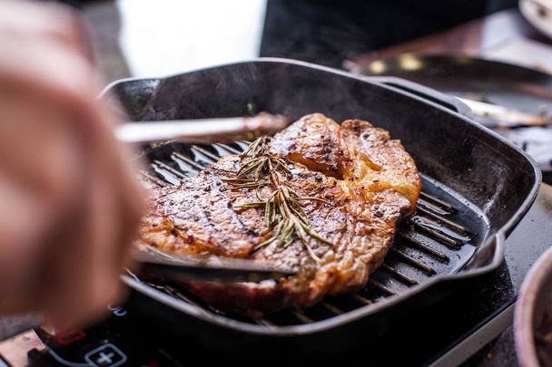 Concept of the correct cooking of meat. The chef prepares, fries a steak of mutton, pork or veal in a frying pan on an induction cooker, with the addition of spices, marinade and wine. Selective focus - Zdjęcie, obraz