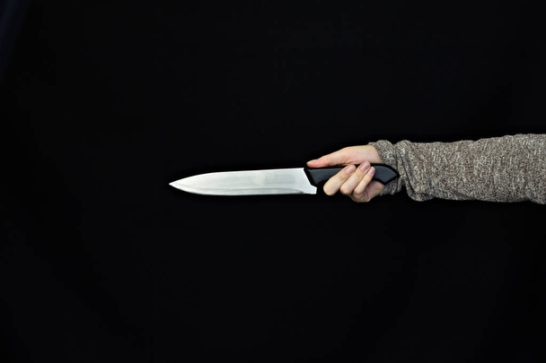 Hand of a girl holding a knife on a black background, close-up - Fotó, kép