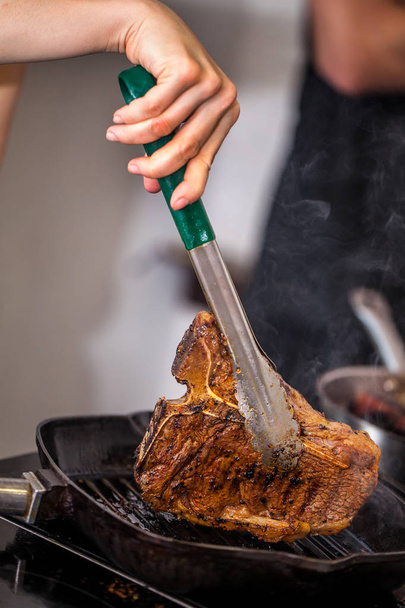 Concept of the correct cooking of meat. The chef prepares, fries a steak of mutton, pork or veal in a frying pan on an induction cooker, with the addition of spices, marinade and wine. Selective focus - Foto, Imagem