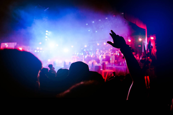 Silhouetten der Hand im Konzert. Licht von der Bühne. Confetti.die Menschenmenge Silhouetten mit den Händen nach oben. Band - Foto, Bild