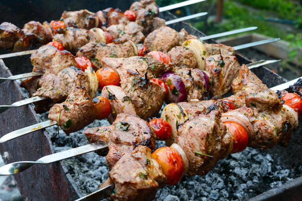 Kebab shish suculento de porco, tomates em espetos, frito em um fogo ao ar livre em um contexto da natureza. Churrasco
. - Foto, Imagem