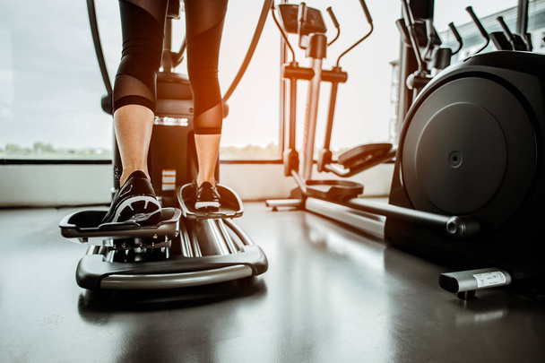 Closeup leg of cardio workout on an elliptical.people working out on an elliptical trainer in gym.Back view  - Foto, Imagem