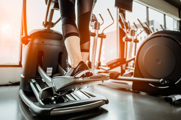 Closeup leg of cardio workout on an elliptical.people working out on an elliptical trainer in gym.Back view  - Фото, изображение