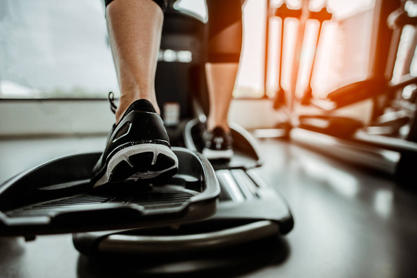 Closeup leg of cardio workout on an elliptical.people working out on an elliptical trainer in gym.Back view  - Φωτογραφία, εικόνα