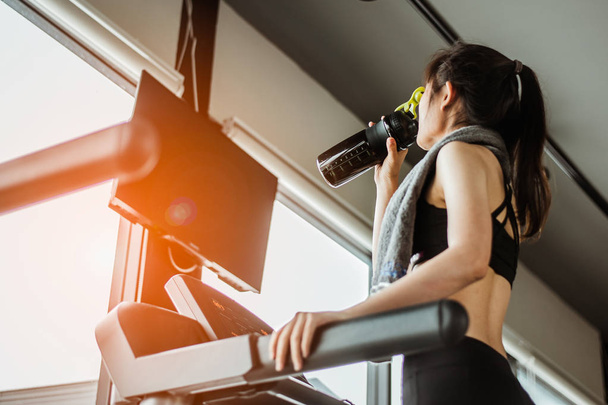 Young woman at treadmill drinking water.Young woman at treadmill drinking .protein shake. - Valokuva, kuva