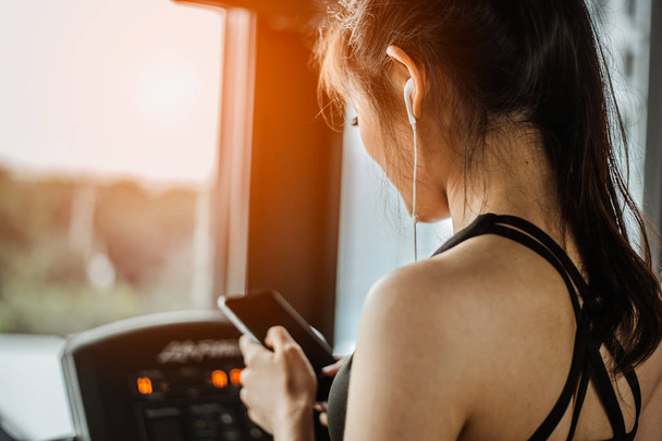 Fitness woman is choosing music to run on a treadmill.exercising concept.fitness and healthy lifestyle. - Foto, Imagen