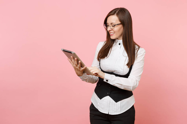 Молодая улыбающаяся успешная красивая деловая женщина держит и с помощью планшетного ПК компьютер изолирован на пастельно-розовом фоне. Леди-босс. Концепция карьерного богатства. Копирование места для рекламы
 - Фото, изображение