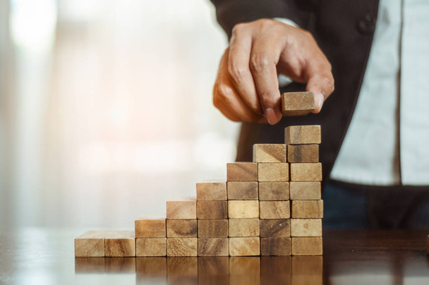 plan and strategy in business.risk concept.hand of man has piling up and stacking a wooden block.Businessman Building The Success. - Photo, Image