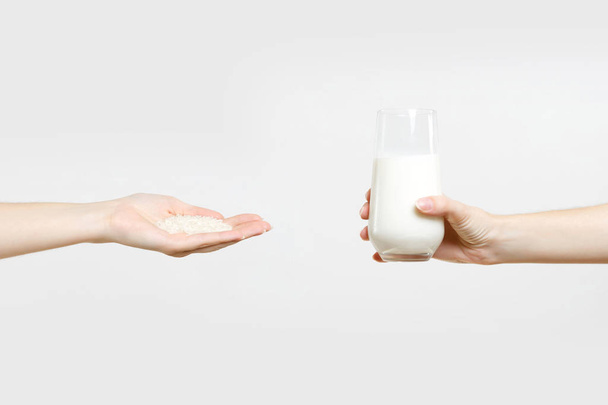 Close up female hold in two hands rice milk in glass, handful of rice isolated on white background. Proper nutrition, vegan vegetarian drink, healthy lifestyle dieting concept. Copy space advertising - Photo, Image