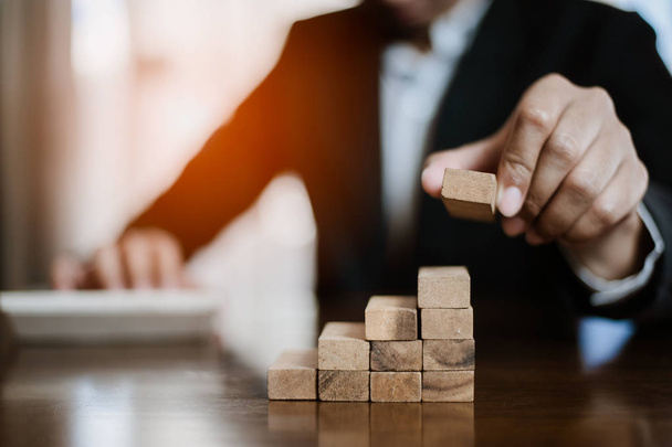 plan and strategy in business.risk concept.hand of man has piling up and stacking a wooden block.Businessman Building The Success.using calculator to calculate. - Fotoğraf, Görsel