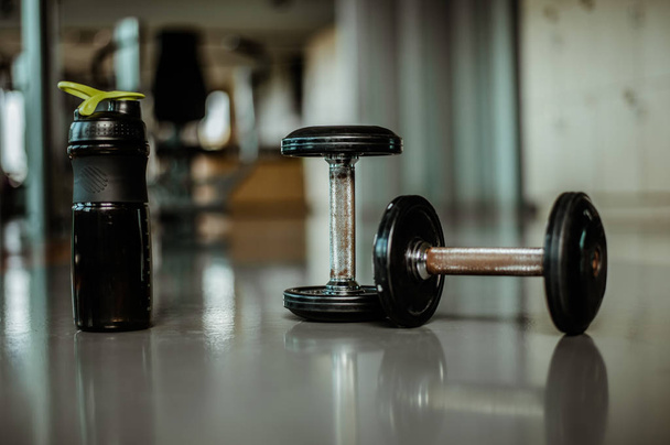two dumbbells for fitness and protein cocktail in a shaker in a gym. Sports nutrition concept - Valokuva, kuva