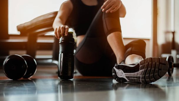 Relaxing after training.beautiful young woman looking away while sitting  at gym.young female at gym taking a break from workout. - Foto, imagen