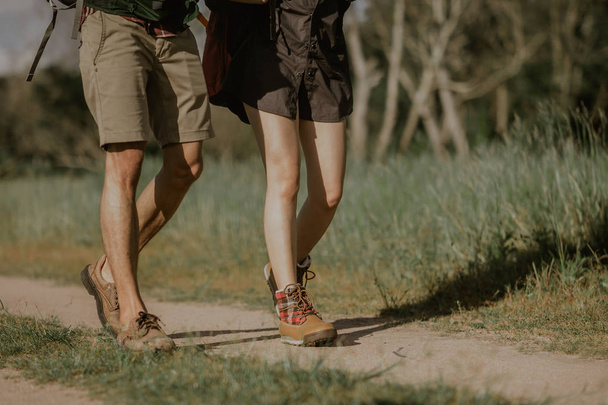バックパック付きのハイカーは、靴に焦点を当てたマウンテンブーツを履いた森林の道を歩く. - 写真・画像