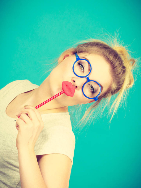 Lovely sweet woman casual style nerdy glasses holding red fake lips on stick having fun, on green blue. Photo take and carnival funny accessories concept. - Fotoğraf, Görsel