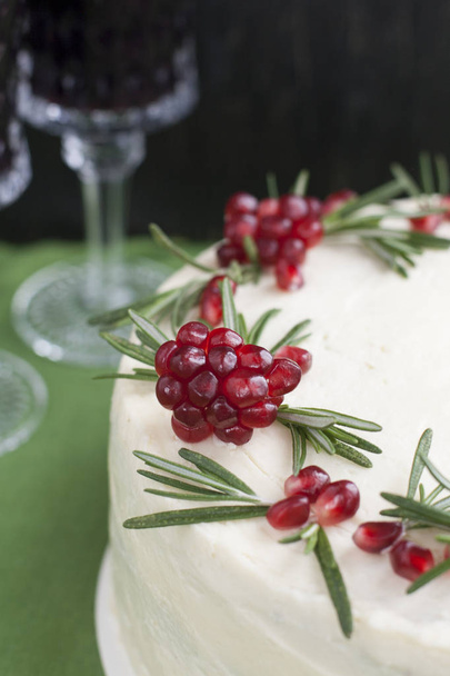 Шоколадный торт с ягодными сливками, кремом из белого сыра, гранатовыми ягодами и розмариновыми ветвями. Идея для праздничного торта или свадебного торта
 - Фото, изображение