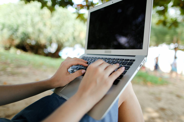 Білі жіночі руки використовують ноутбук з піском на фоні, чорний екран
. - Фото, зображення