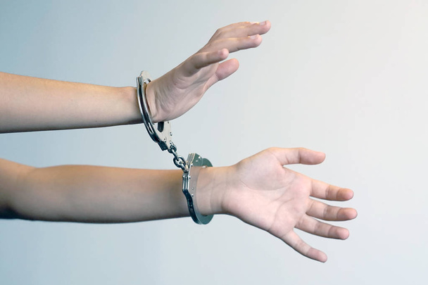 Arrested woman handcuffed hands. Prisoner or arrested terrorist, close-up of hands in handcuffs isolated. Criminal female hands locked in handcuffs. Close-up view - Photo, Image