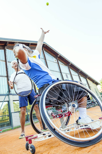 tennis coach teaching a disabled player the correct movement of the service - Photo, image