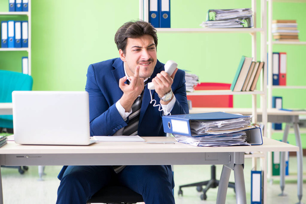 Uomo d'affari infelice con il lavoro eccessivo seduto in ufficio  - Foto, immagini