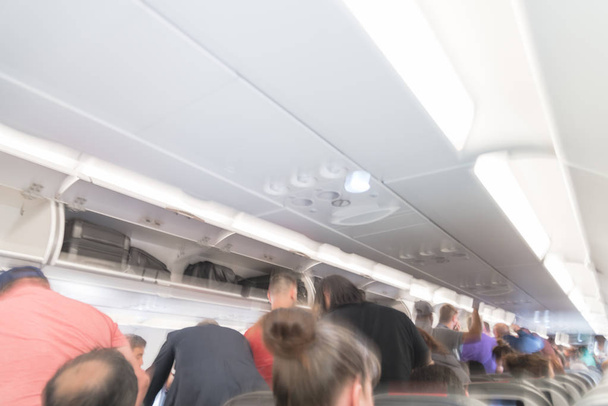 Θολή φόντο εσωτερικό του μεγάλου αεροπλάνου με ανθρώπους που στέκεται στο διάδρομο σε αναμονή για να πάρετε μακριά. Κάθισμα συνοδηγού στο εσωτερικό του αεροσκάφους. Έννοια του ταξιδιού - Φωτογραφία, εικόνα