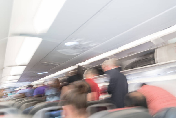 Interior borroso de fondo de un avión grande con gente de pie en el pasillo esperando a bajar. Asiento de pasajeros dentro de la aeronave. Concepto de viaje
 - Foto, Imagen