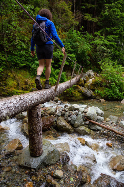 Hiking on a wooden bridge across a river creek in the woods. Taken on the trail to the top of Brunswick Mountain, North of Vancouver, BC, Canada. - Foto, Bild