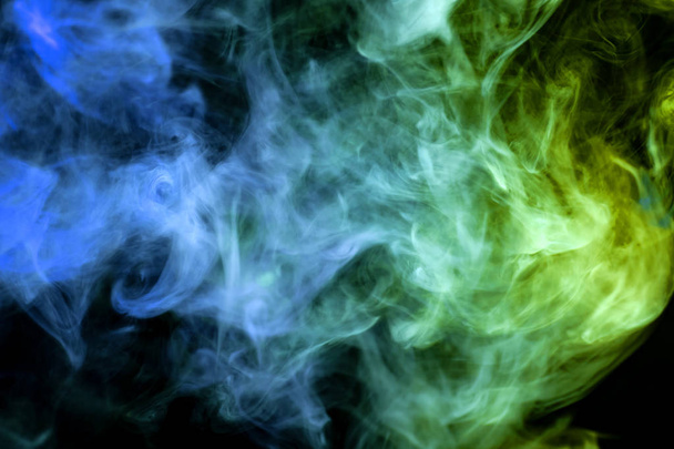 Dense multicolored smoke of   blue and green colors on a black isolated background. Background of smoke vap - Foto, Imagen