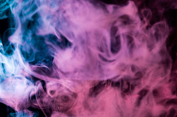 Humo denso multicolor de colores azul, rosa y púrpura sobre un fondo negro aislado. Antecedentes de humo vap
 - Foto, Imagen