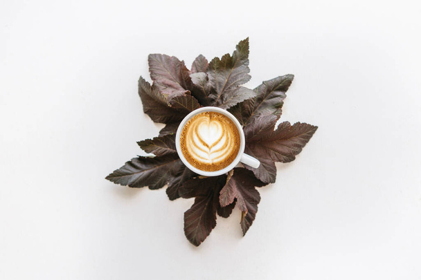 Šálek voňavé kávy cappuccino. Nedaleko leží podzimní listí. - Fotografie, Obrázek