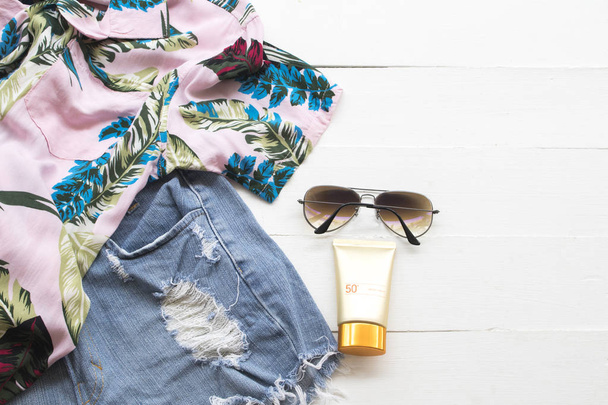 cosmético natural para pele rosto protetor solar spf50, óculos de sol, calças curtas jeans e camisa da mulher relaxar verão no fundo branco de madeira
 - Foto, Imagem