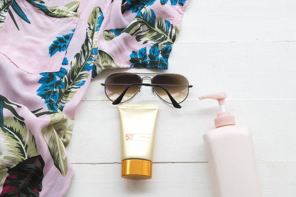 cosméticos naturais para pele rosto protetor solar spf50, óculos de sol, loção corporal e camisa da mulher relaxar verão no fundo branco de madeira
 - Foto, Imagem
