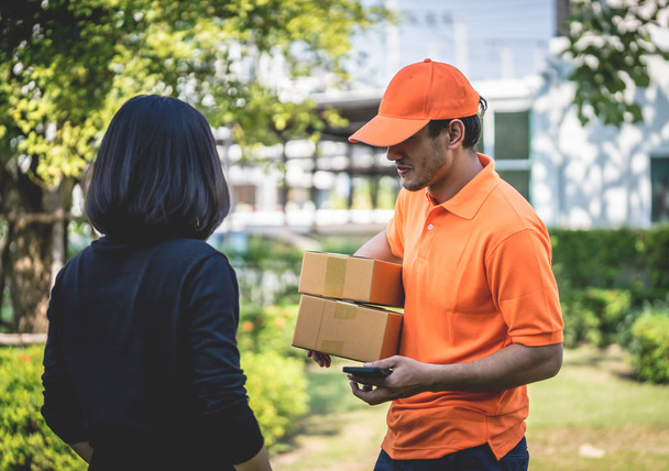 Entrega homem em laranja está entregando pacotes para uma mulher
 - Foto, Imagem
