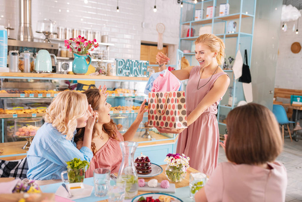 Beaming blonde-haired guest making presents attending baby shower - Foto, Imagen