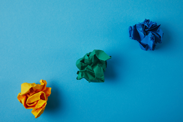 top view of colorful crumpled papers on blue surface - Foto, Imagem