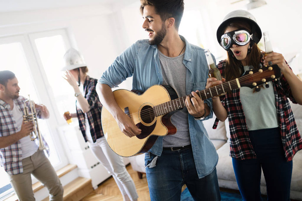 Cheerful young friends having party together and playing instruments - Foto, imagen