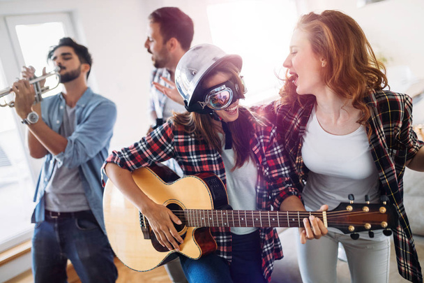 Cheerful young friends having party together and playing instruments - Foto, Imagen