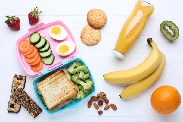 Iskolai ebéd-box a zöldségek és gyümölcsök a fehér fa asztal - Fotó, kép