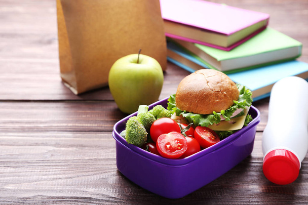 School lunch box with sandwich and vegetables on wooden table - Zdjęcie, obraz