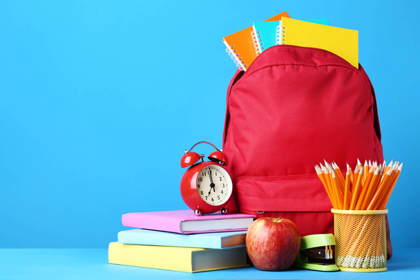 Red backpack with school supplies on blue background - Zdjęcie, obraz